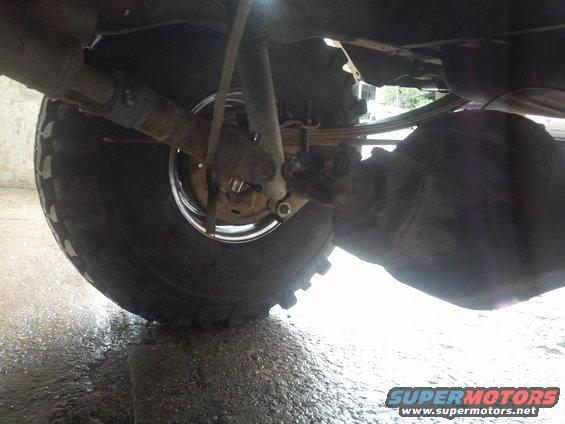 Underside view of a vehicle's rear axle, leaf springs, and shock absorber