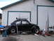 1964 Volkswagen Beetle - A modified black 1964 Volkswagen Beetle sits outside a garage, equipped with a roof rack and off-road tires.