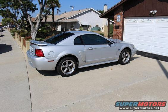 Silver 2002 Ford Mustang parked in a driveway next to a garage