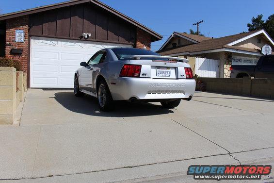 Silver 2002 Ford Mustang GT parked in front of a garage, rear view