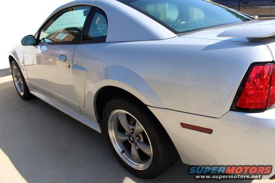 Silver 2002 Ford Mustang coupe, rear quarter panel and side view, showing a spoiler and aftermarket wheels