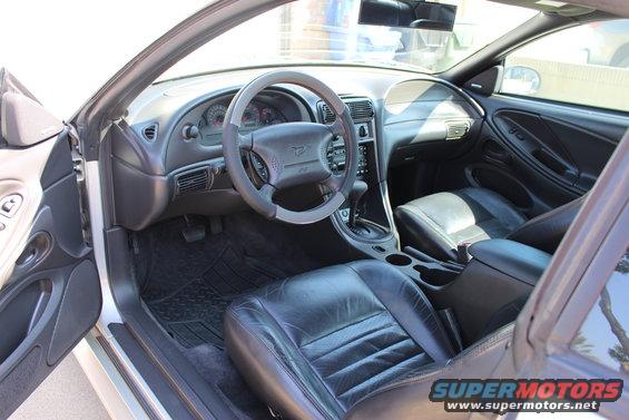 Black leather interior of a 2002 Ford Mustang, showing the dashboard, steering wheel, and front seats