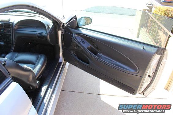 Interior shot of a 2002 Ford Mustang showing the driver's side door panel, dashboard, and leather seat