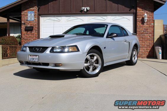 Silver 2000 Ford Mustang coupe with a hood scoop, parked in a driveway