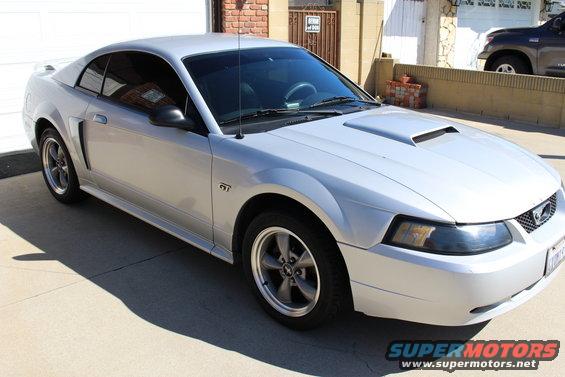 Silver 2002 Ford Mustang GT coupe parked on concrete driveway, front passenger side visible