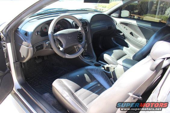 Interior of a silver 2000 Ford Mustang with black leather seats, dashboard, and steering wheel