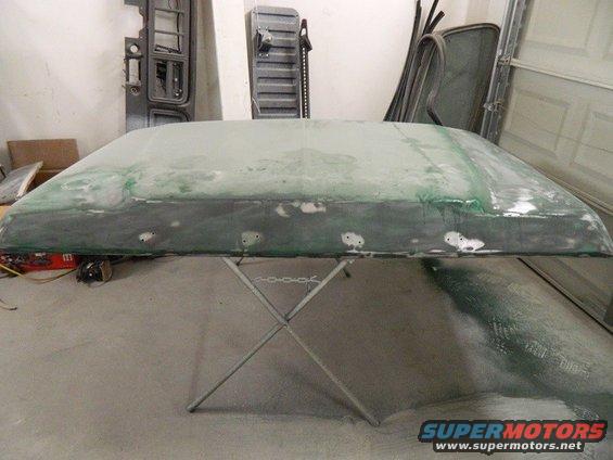 Car roof section on a stand, covered in primer and body filler