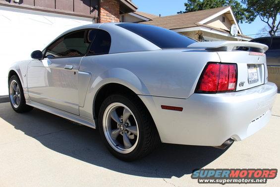 Silver 2004 Ford Mustang GT coupe with a rear spoiler and tinted windows parked in a driveway