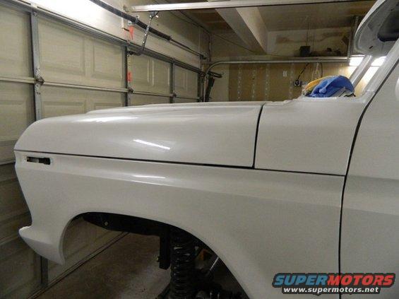 White 1979 Ford Bronco fender and hood in garage. Supermotors.net logo visible