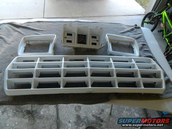 White grille, headlight bezels, and instrument cluster laid out on a cloth