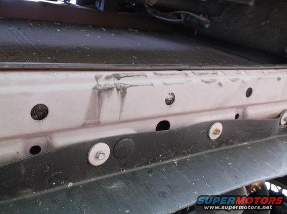 Close-up of car's radiator support area with some dirt and rust marks