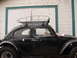 1964 Volkswagen Beetle - This black Volkswagen Beetle is equipped with a roof rack and parked in front of a white garage door.