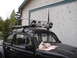 1964 Volkswagen Beetle - A black 1964 Volkswagen Beetle is equipped with a roof rack and four auxiliary lights, parked in front of a building.