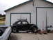 1964 Volkswagen Beetle - Side view of a black 1964 Volkswagen Beetle with a roof rack, parked outside a garage with tools nearby.