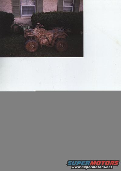 Muddy ATV parked on grass in front of a house