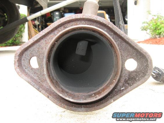 Close-up of a rusty exhaust pipe flange with the pipe opening visible