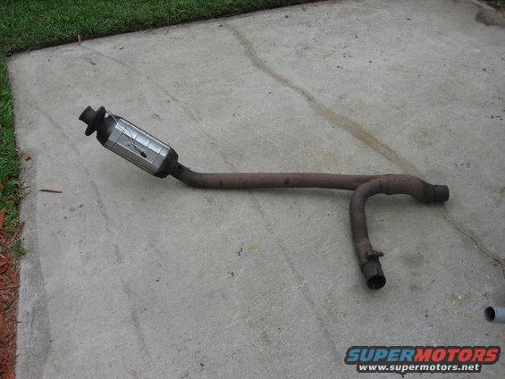 Exhaust pipe and catalytic converter removed from a vehicle, lying on concrete