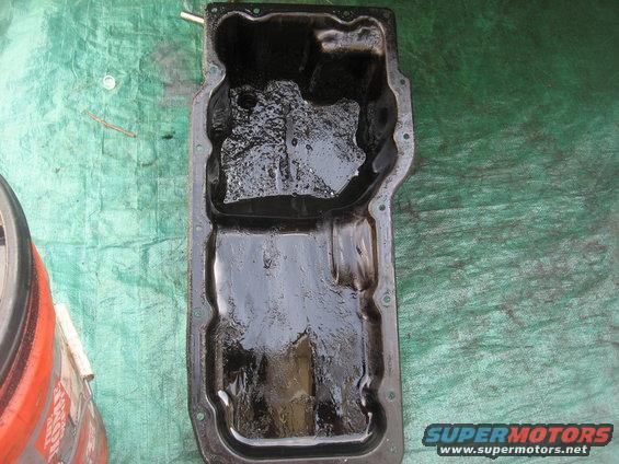Oil pan with sludge, on a green tarp