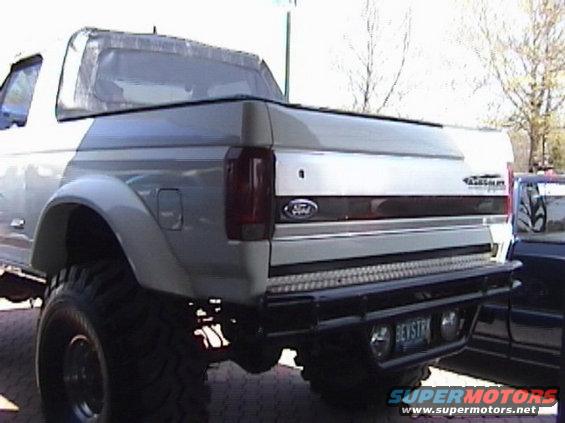 Silver Ford Bronco rear with custom bumper and large tires. License plate reads 'BEVSTRK'
