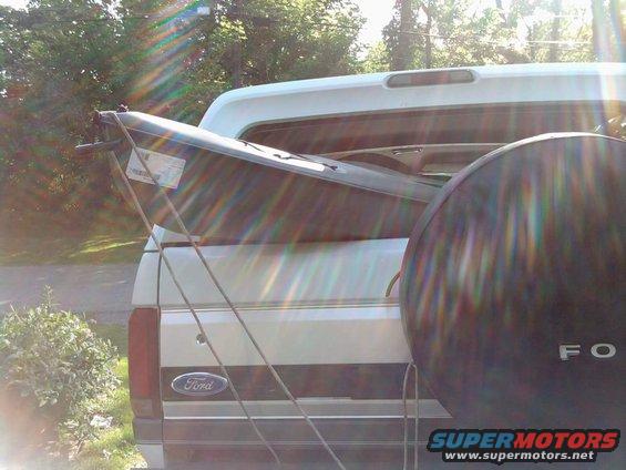 Ford pickup truck with a kayak strapped to the bed. Spare tire visible on the right