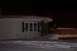 1988 Chevrolet Silverado 2500 - A winter night scene shows a snow-covered house and yard with a wooden fence.