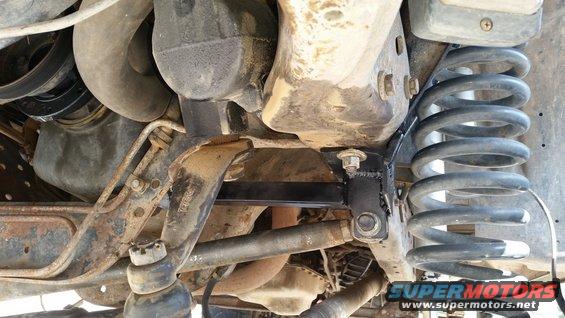 Undercarriage view of vehicle suspension with coil spring and metal bracket