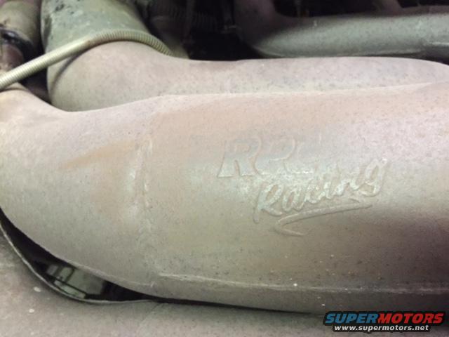 Exhaust pipe with embossed "K&N Racing" logo, showing signs of wear and dust