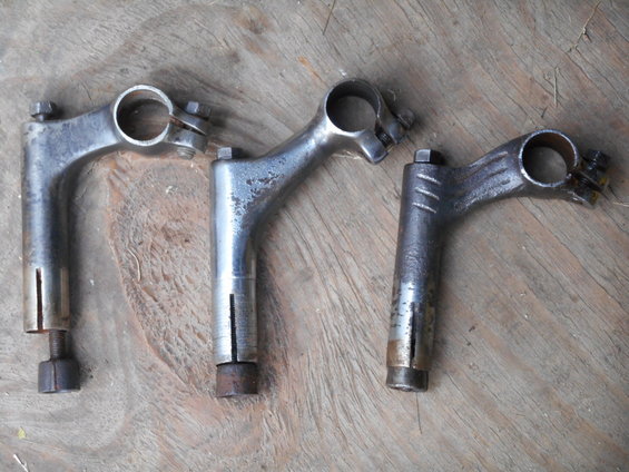 Three bicycle handlebar stems on a wooden surface