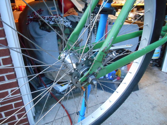close-up of green bicycle frame and rear wheel with spokes