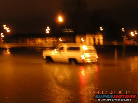 White SUV driving through floodwaters at night, timestamp 2004.02.06 00:11
