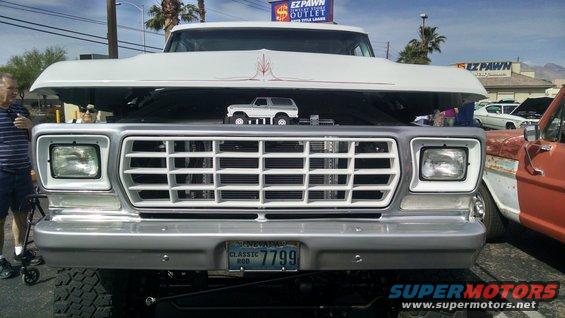 White 1977 Ford F-Series truck front grille with hood open, showing a toy Bronco