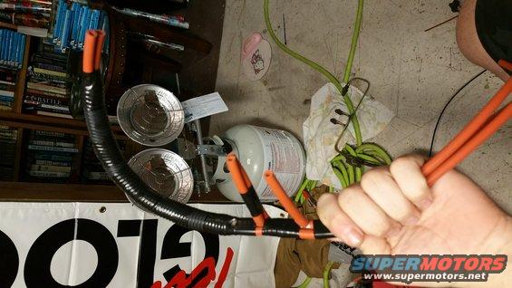 Black corrugated tubing with orange vacuum lines, propane tank, and Supermotors logo