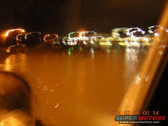 Streaks of light reflect on a wet surface at night