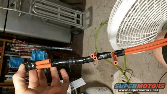 Hand holding modified vacuum lines with orange tubing and black protective wrap
