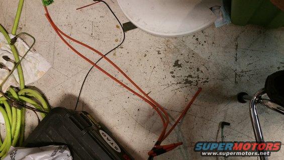 Wires, a black toolbox with a 'Stag' sticker, and some green tubing on a concrete floor