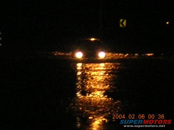 Car headlights reflected on a dark, wet road at night
