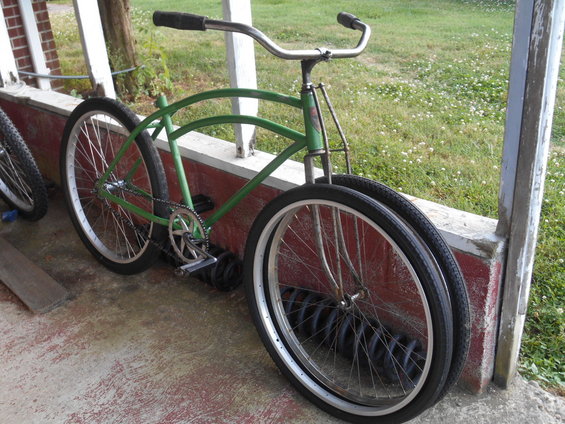Green bicycle with chrome handlebars and whitewall tires