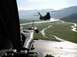 1981 Ford Bronco - A view from a helicopter gunner's position shows a second helicopter flying over a winding river in a mountainous valley.