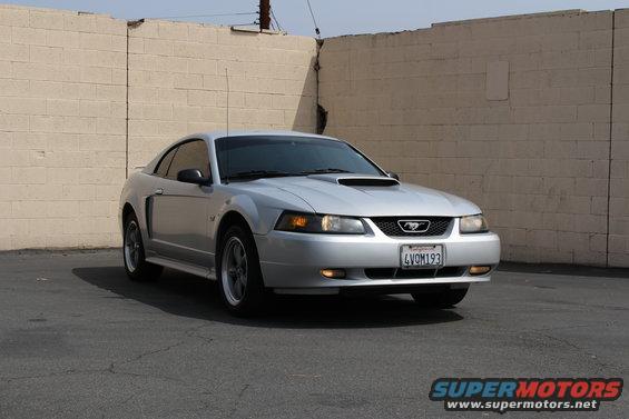 Silver 2002 Ford Mustang parked in front of a brick wall. License plate reads 4VOM193
