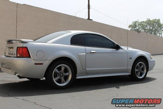 Silver 2002 Ford Mustang coupe with a rear spoiler and tinted windows, viewed from the side