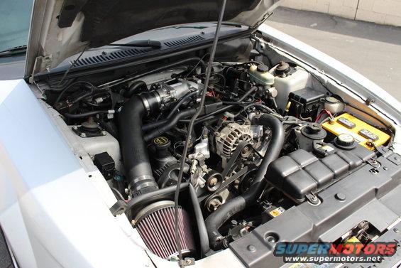 2002 Ford Mustang engine bay with aftermarket air intake and yellow battery
