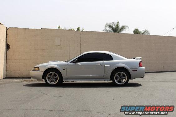 Silver 2002 Ford Mustang coupe parked by a brick wall