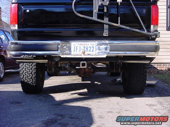 Black pickup truck rear with Virginia license plate JFJ-7822 and hitch receiver. Another vehicle is parked to the left