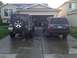 2004 Jeep Grand Cherokee - Two SUVs are parked in a driveway in front of a garage. The Jeep Grand Cherokee is a 2004 model.