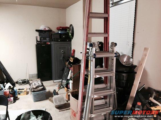 Garage interior with two safes, ladders, storage bins, and various tools