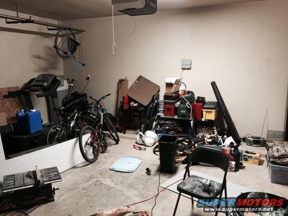 Cluttered garage with treadmills, bicycles, tools, and storage shelves