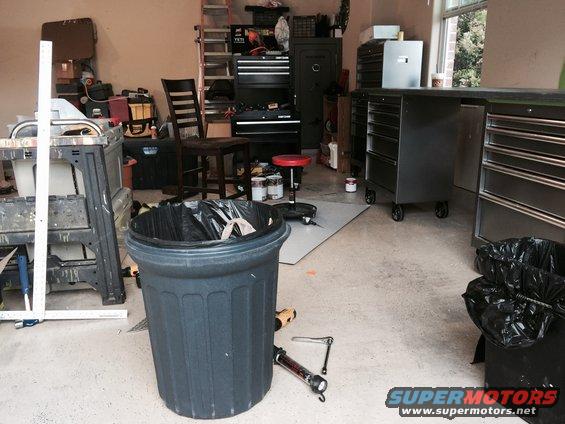 Garage scene with a trash can, tool chests, ladder, and workbenches