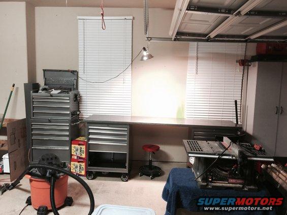 Garage workshop with tool chests, workbench, and a table saw. A shop vac is in the foreground