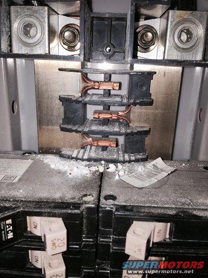 Electrical breaker panel with copper wiring and circuit breakers, covered in white dust