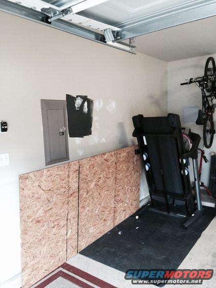 Garage interior with treadmill and bicycle mounted on wall